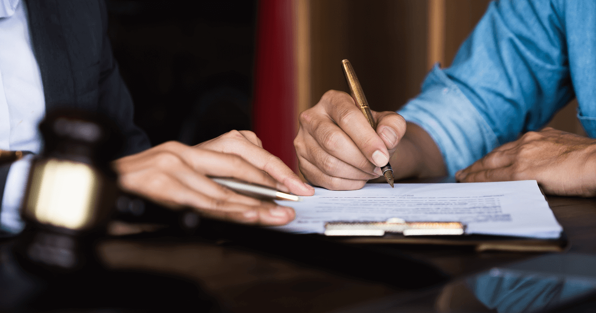 Close-up of two pairs of hands signing paper