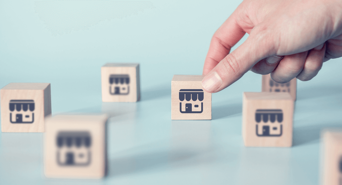 Hand picking up small wooden block with icon of a shop printed on front