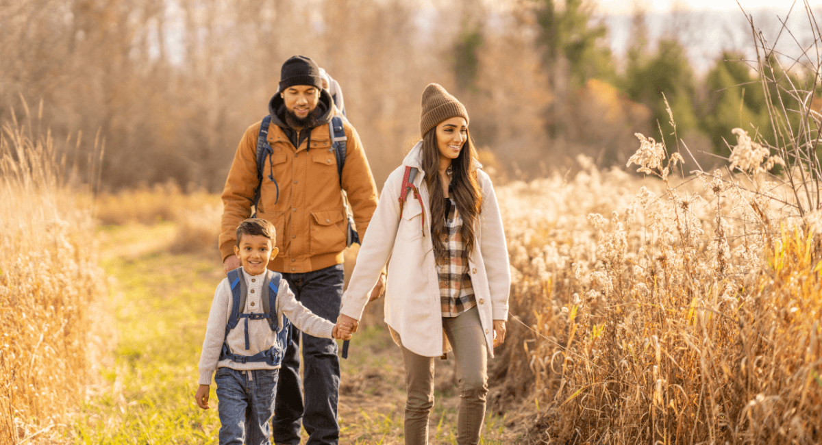 Family in autumn clothing walking through a wheat field holding hands